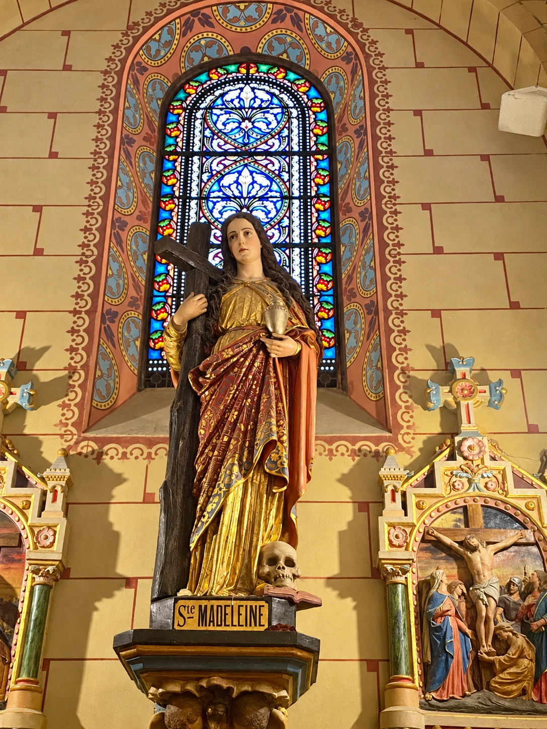 Imagem de Maria Magdalena diante de um vitral.