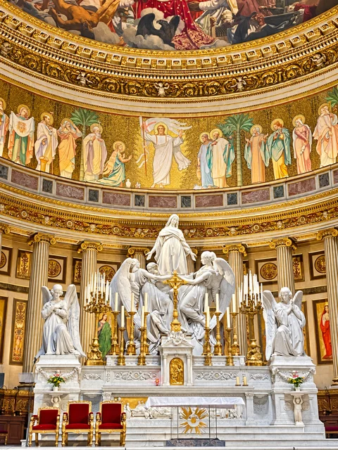 Altar com esculturas brancas sob pinturas douradas.